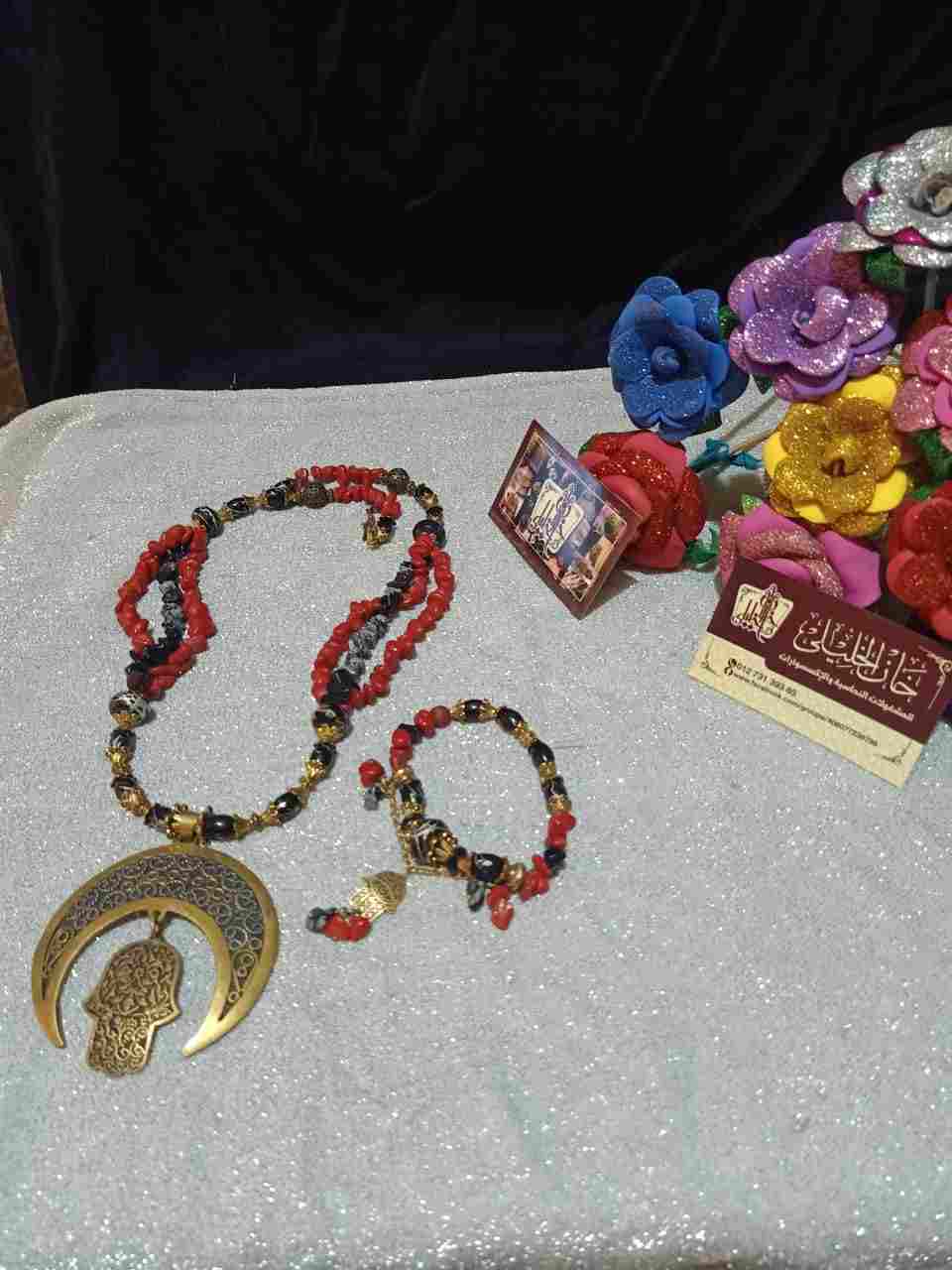 Two-piece set of a large copper pendant, a crescent and a palm with a black and red fracture, black and red beads, with metal dividers, a small palm collar, and a red and brown fracture