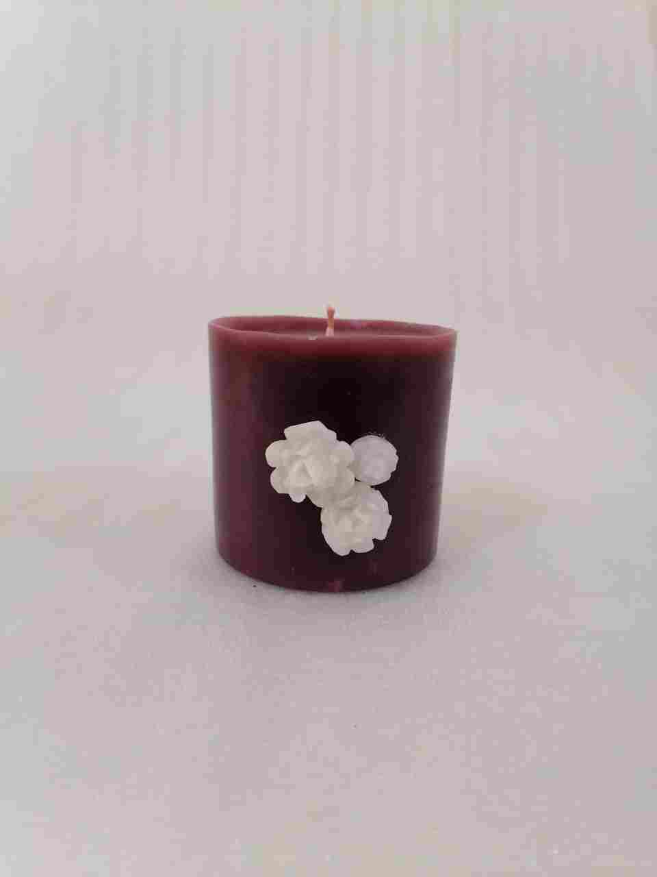 A circular candle with the scent of oud decorated with roses of wax