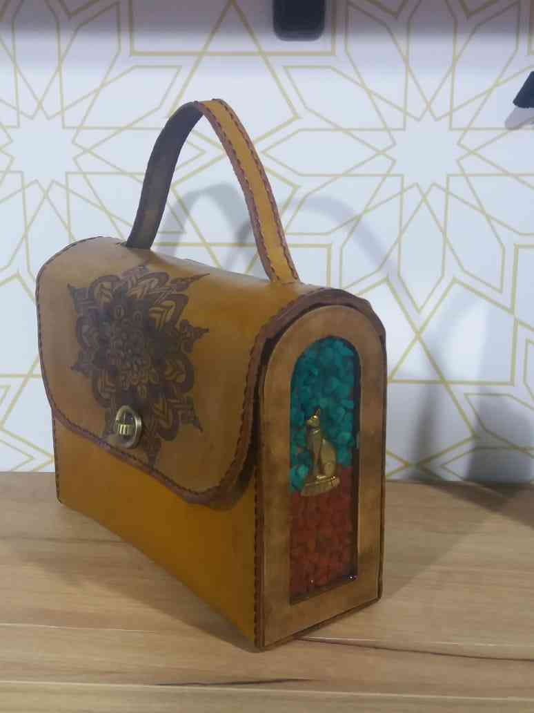 Un pequeño bolso cruzado y una mano pequeña y en medio de cuero italiano Bull-Up con lados de madera, piedras y trabajos de resina.