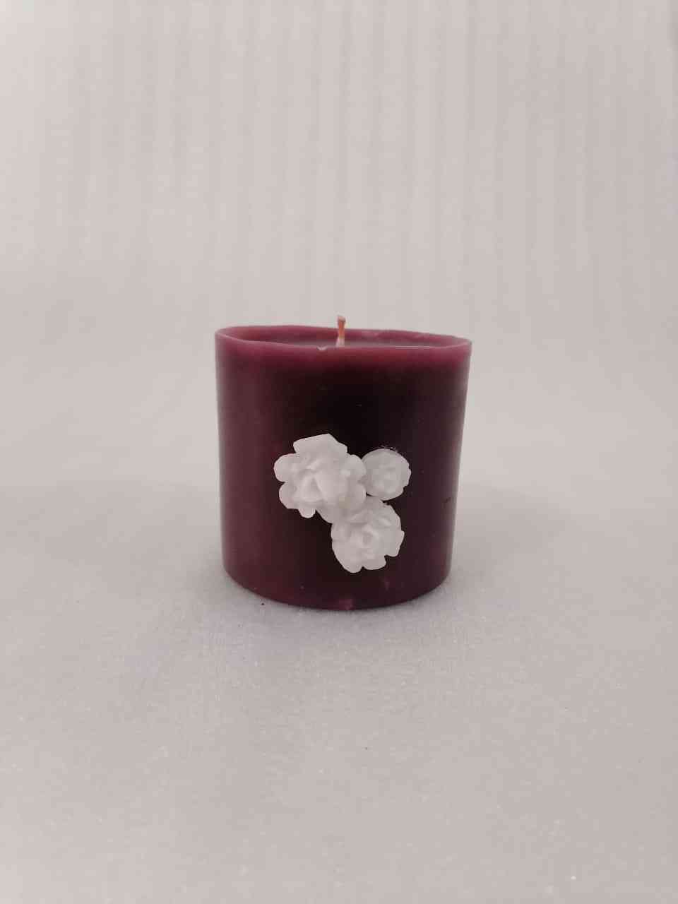 A circular candle with the scent of oud decorated with roses of wax