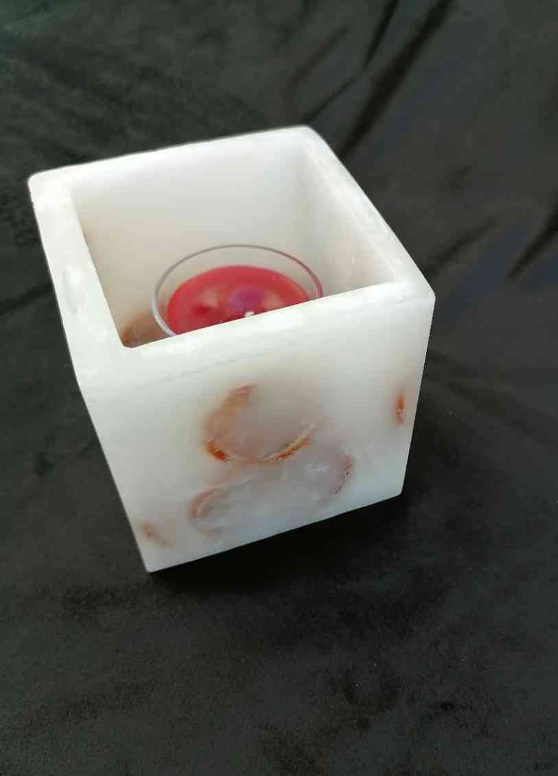 A square candle with a lemon inside