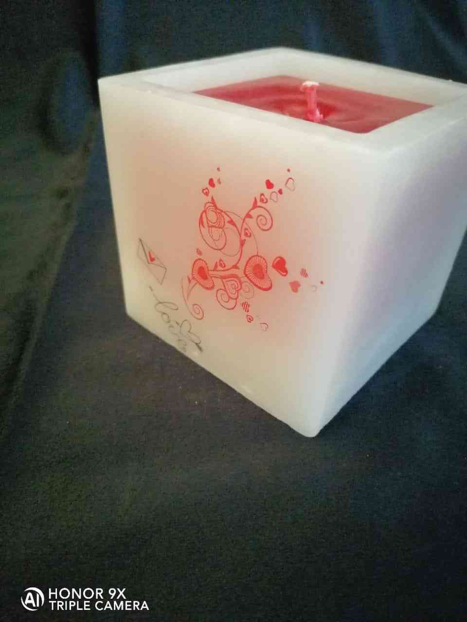 A square candle with wax smelling roses inside