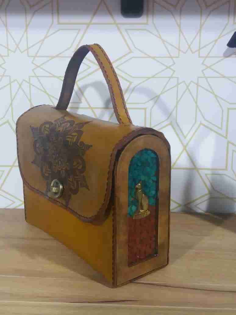 Un pequeño bolso cruzado y una mano pequeña y en medio de cuero italiano Bull-Up con lados de madera, piedras y trabajos de resina.